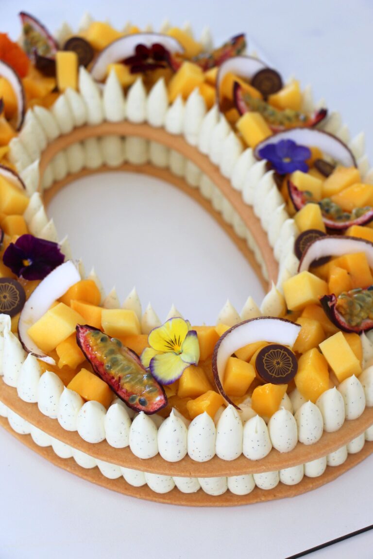 Number Cake exotique garni de mangue fraîche, fruit de la passion, noix de coco, crème vanille de Madagascar et fleurs comestibles, réalisé par Précieux Délices à Orléans.